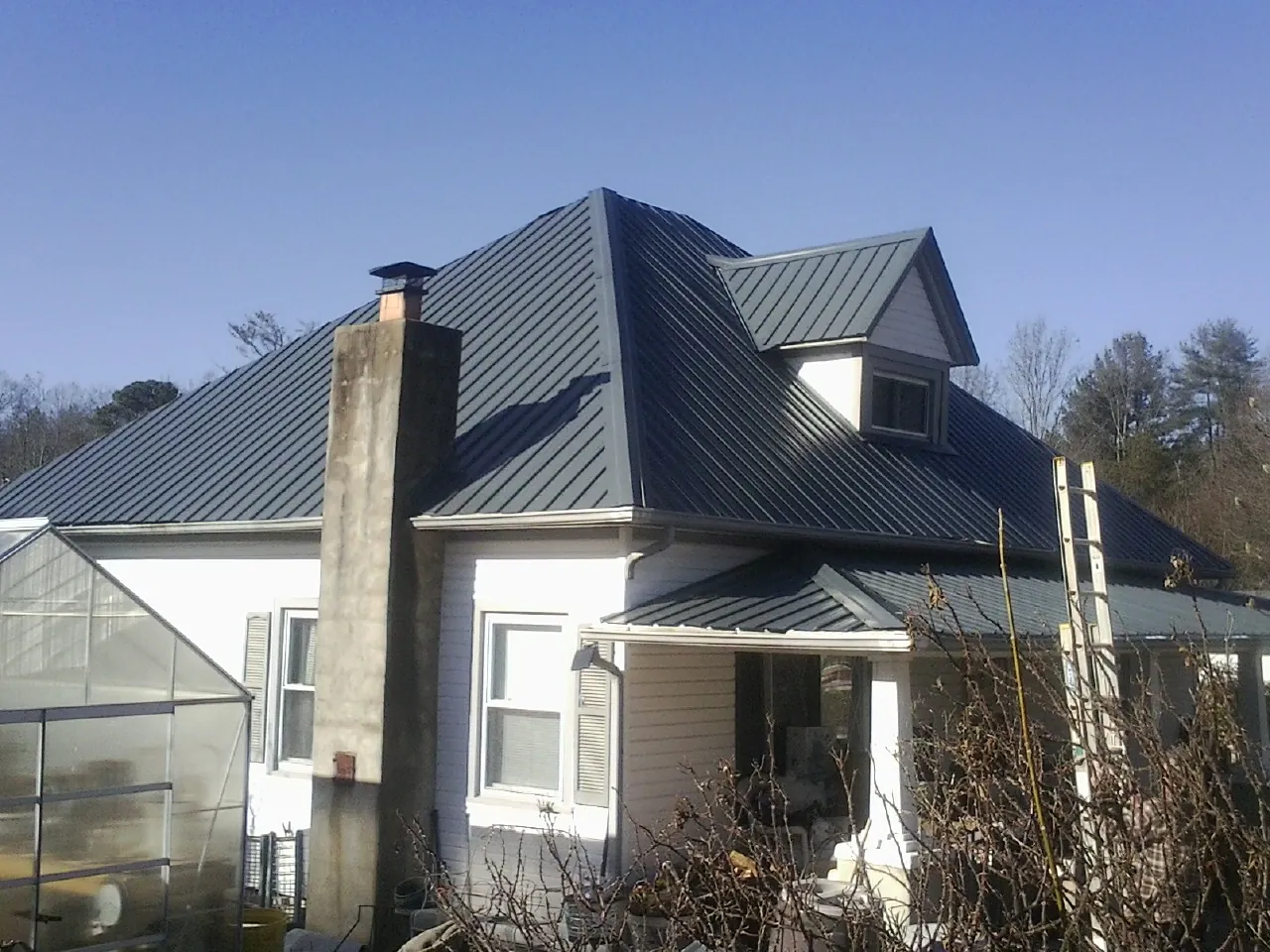 Dark blue standing seam metal roof on a white farmhouse with dormer — Slate & Tile Roof Repair by Roofing Brothers in Depoe Bay