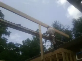 Carpenter setting a ridge beam over a new addition frame — Ice Dam Removal by Roofing Brothers in Depoe Bay