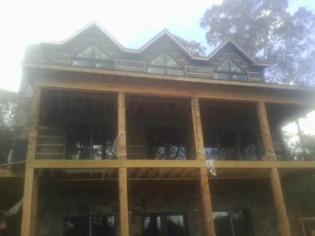 Dormers and porch framing on a large log home under construction — Roof Coating work by our crew in Depoe Bay