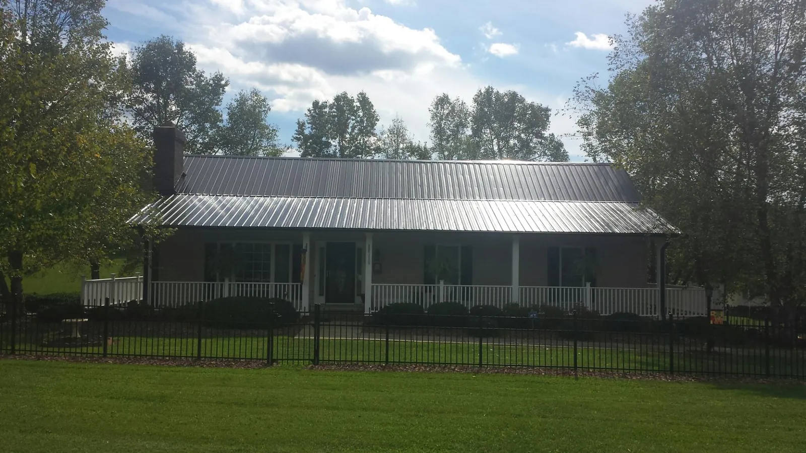 Gray metal roof on a brick ranch with a full width front porch — Gutter Guard Installation work by our crew in Depoe Bay