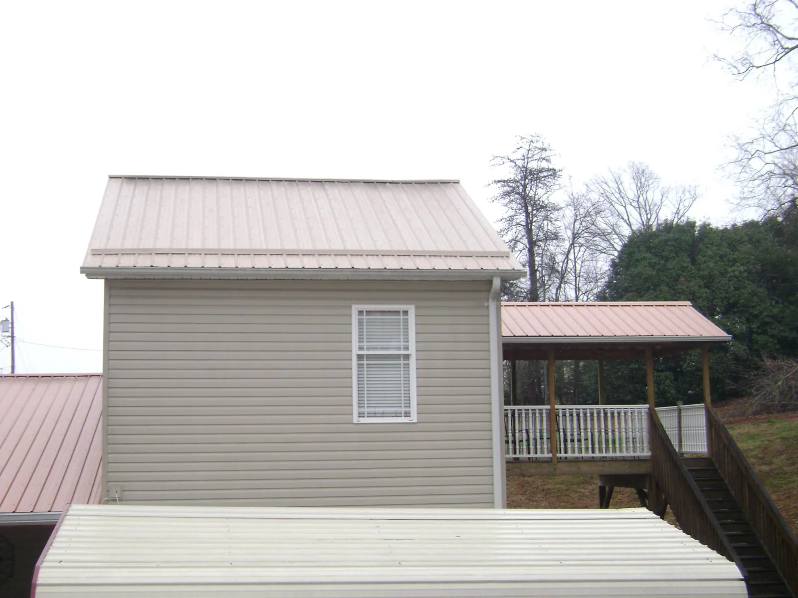 Tan metal roofs on a two story addition and attached porch, from a Roof Replacement job in Depoe Bay